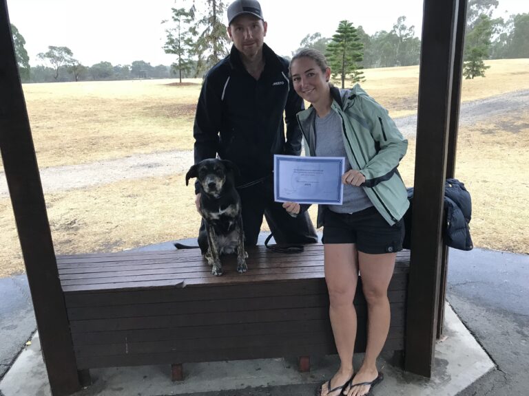 Happy dog trainer and owner celebrating certification outdoors.