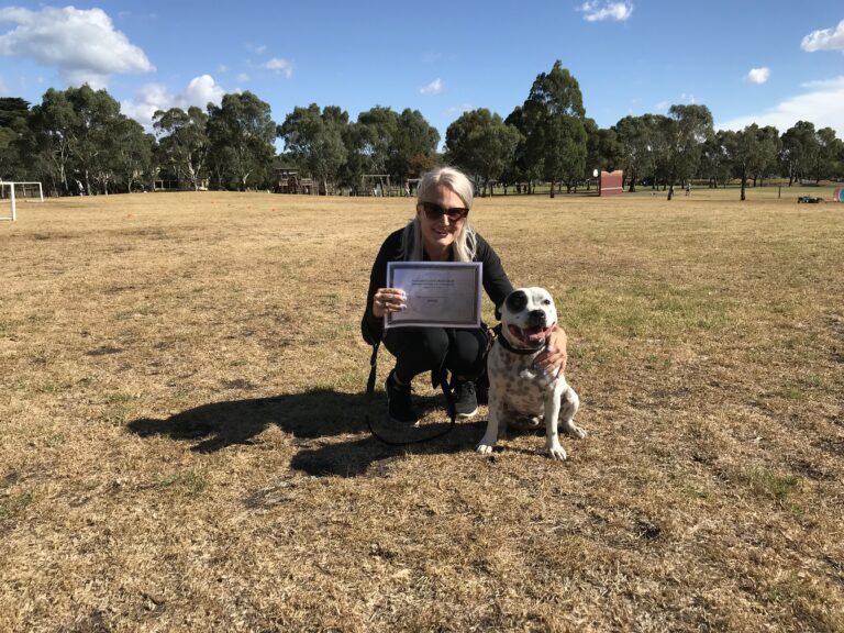 Woman with her dog celebrating dog training certification outdoors.