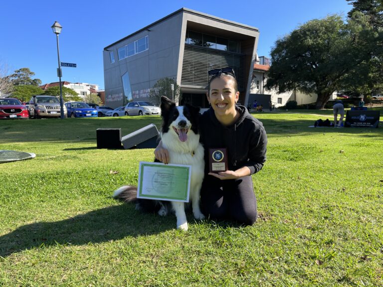 Dog training certification award with a happy dog and trainer outdoors.