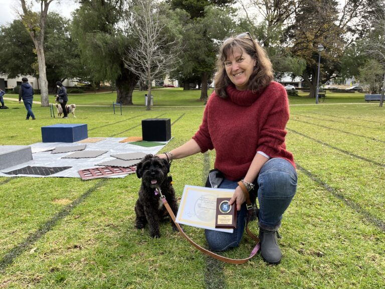 Dog training session with a smiling woman and her dog outdoors.