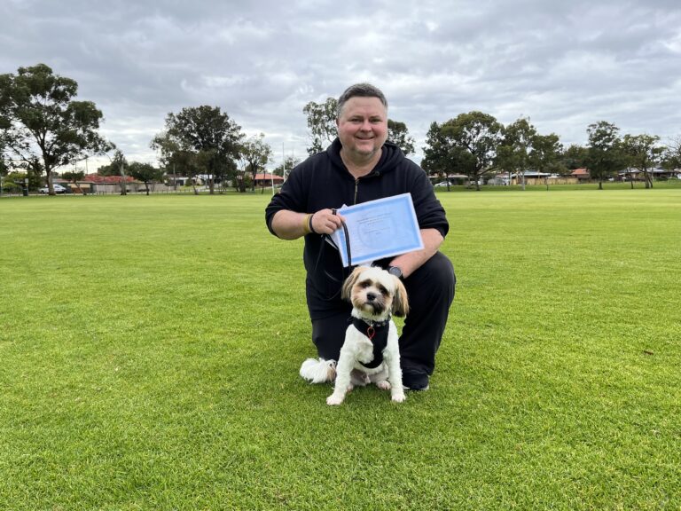 Happy man with dog during agility training session outdoors.