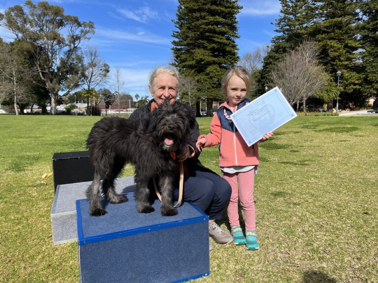 Happy girl with her dog and trainer during agility training session outdoors.