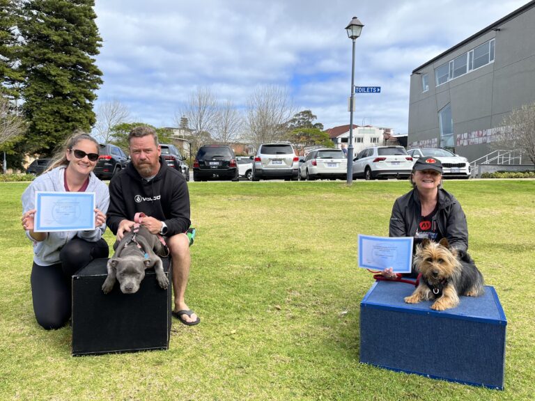 Happy dog owners with their certified dogs outdoors at Agile Dogs training event.
