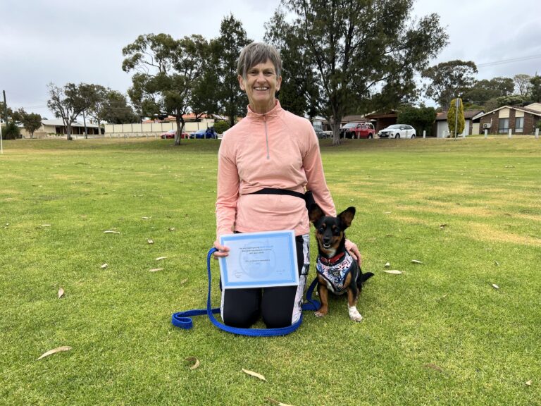 Happy woman with her dog during dog training certification event in a park.