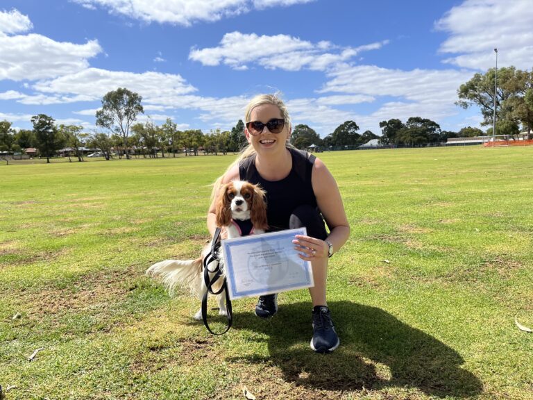 Woman with her dog celebrating dog training certification outdoors.