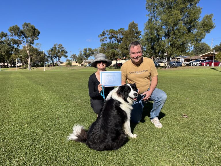 Happy dog owner and trainer celebrating with a black and white Border Collie in a park.