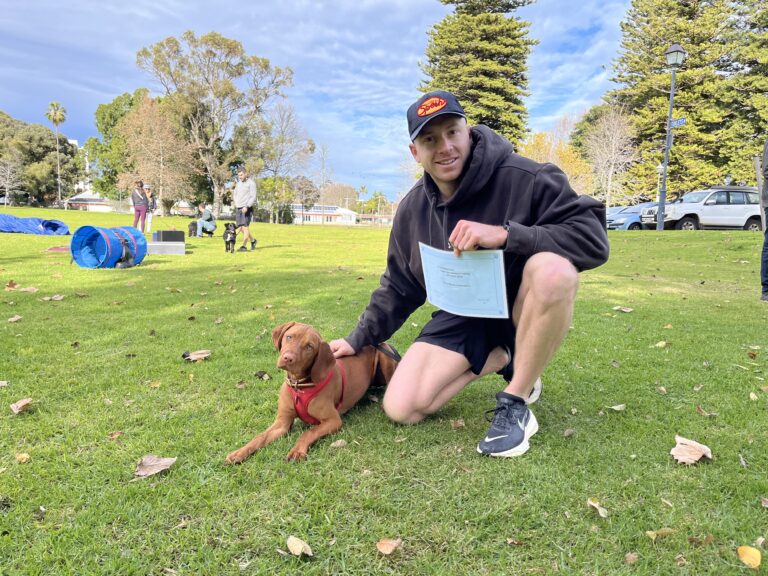 Young man training a dog outdoors at Agile Dogs dog training session.