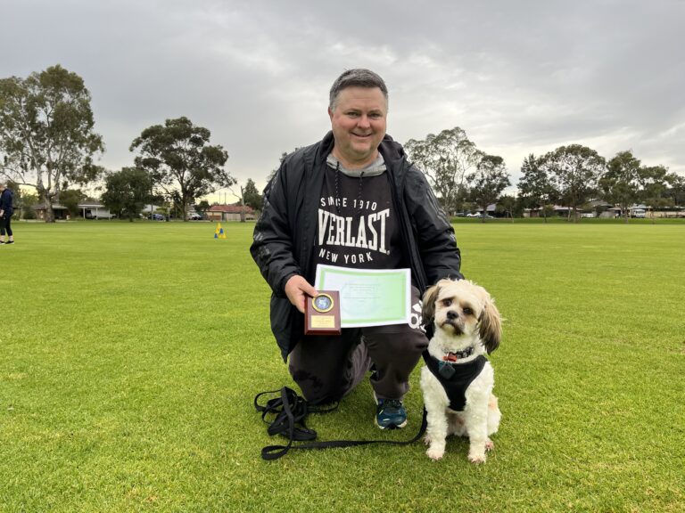 Happy dog and owner celebrating agility success outdoors.
