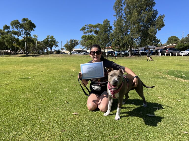 Happy woman with dog celebrating dog training success outdoors.