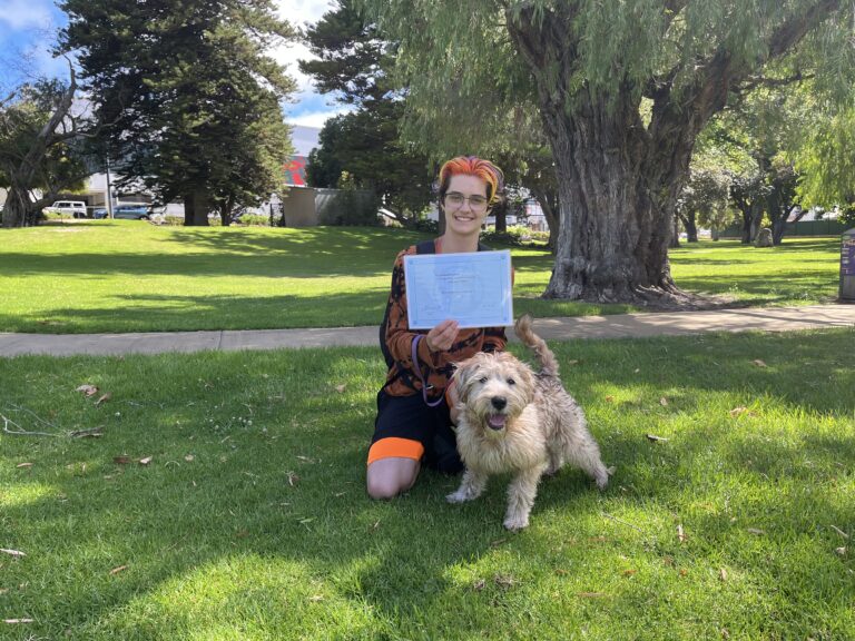 Woman with dog celebrating dog training success outdoors.
