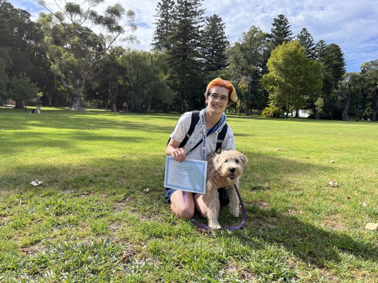 Dog training certification outdoors in park with trainer and dog.