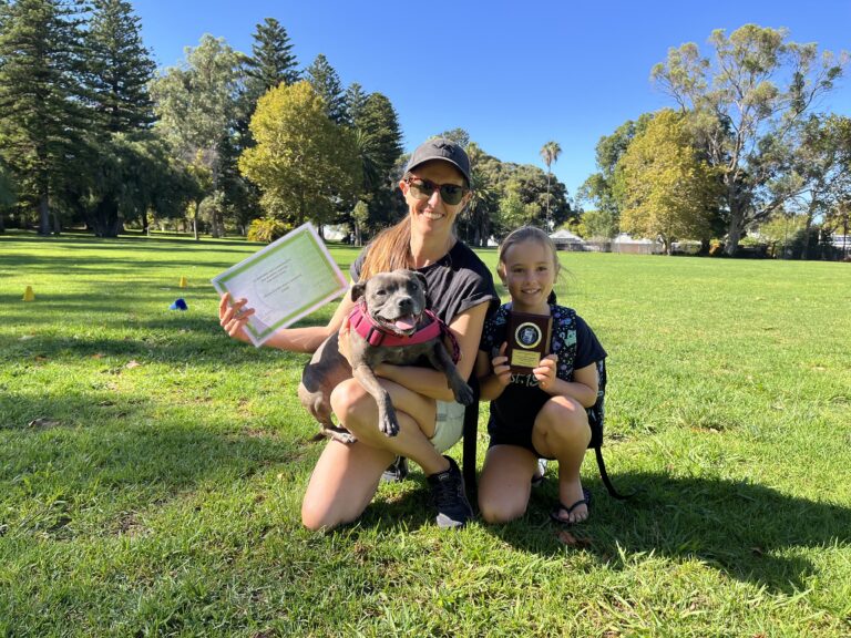 Woman, girl, and dog celebrating success after dog training session outdoors.
