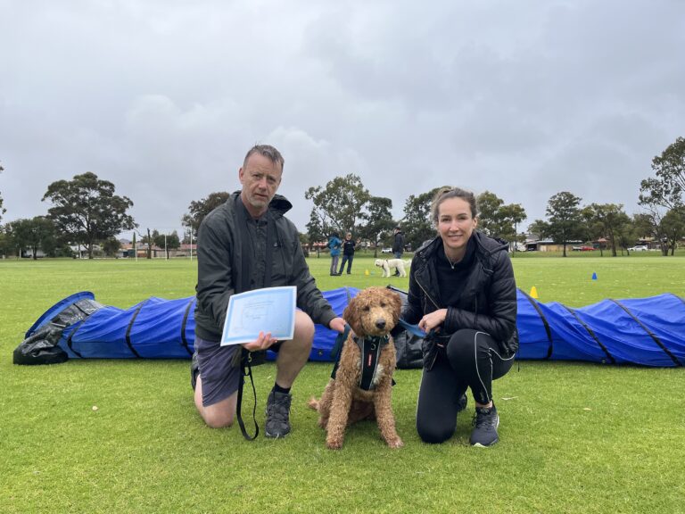 Dog agility training session at Agile Dogs with handler and trainer outdoors.