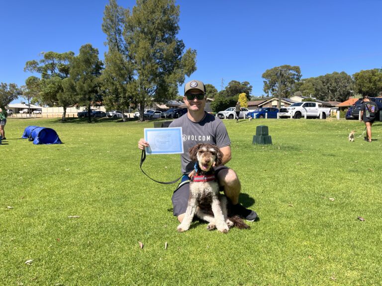 Man with dog celebrating dog training certification outdoors.