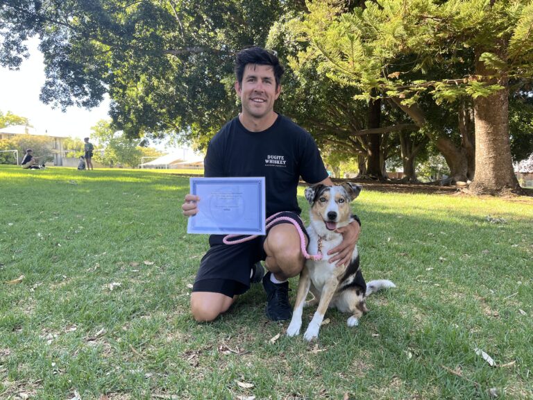 Man with dog celebrating dog training success outdoors.